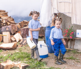 Enfants de la famille Moret portant les bidons de lait pour nourrir les veaux