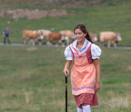 Jeune fille en costume marchant sur le chemin de la désalpe, Gruyère