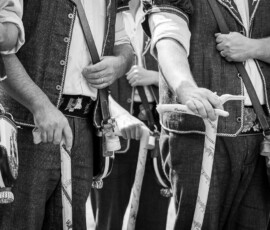 Mains et costumes d'armaillis tenant les cannes, photo en noir et blanc.